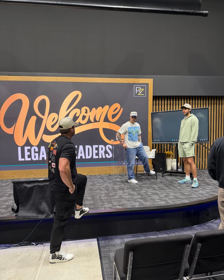 Maxwell Mayes on stage with two others in front of a Welcome Legacy Leaders backdrop.
